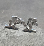 A pair of sterling silver earrings with clear cubic zirconia decorations in a branch pattern, displayed on a textured grey background.